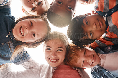 Buy stock photo Low angle shot of a group of cheerful elementary school kids forming a huddle and looking down at the camera during the day