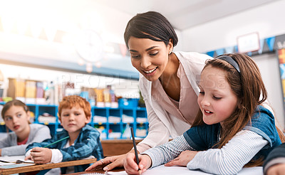 Buy stock photo Shot of a cheerful young female teacher helping a student inside of the class at school