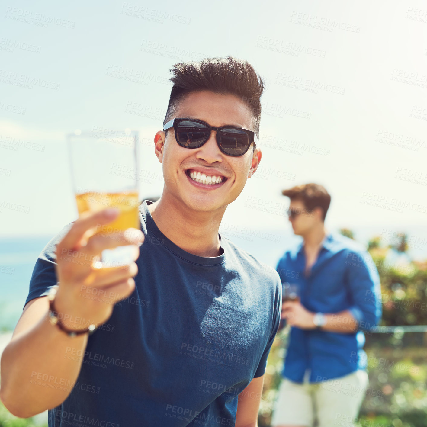 Buy stock photo Portrait of a handsome young man raising up his glass for a toast while relaxing outdoors with his friends