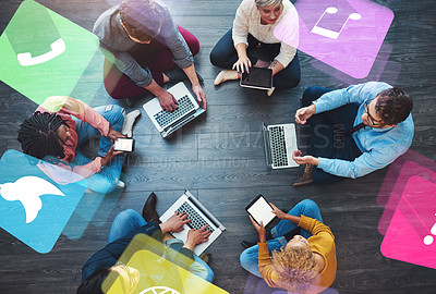Buy stock photo High angle shot of a group of businesspeople sitting down on the floor and using their digital devices at work