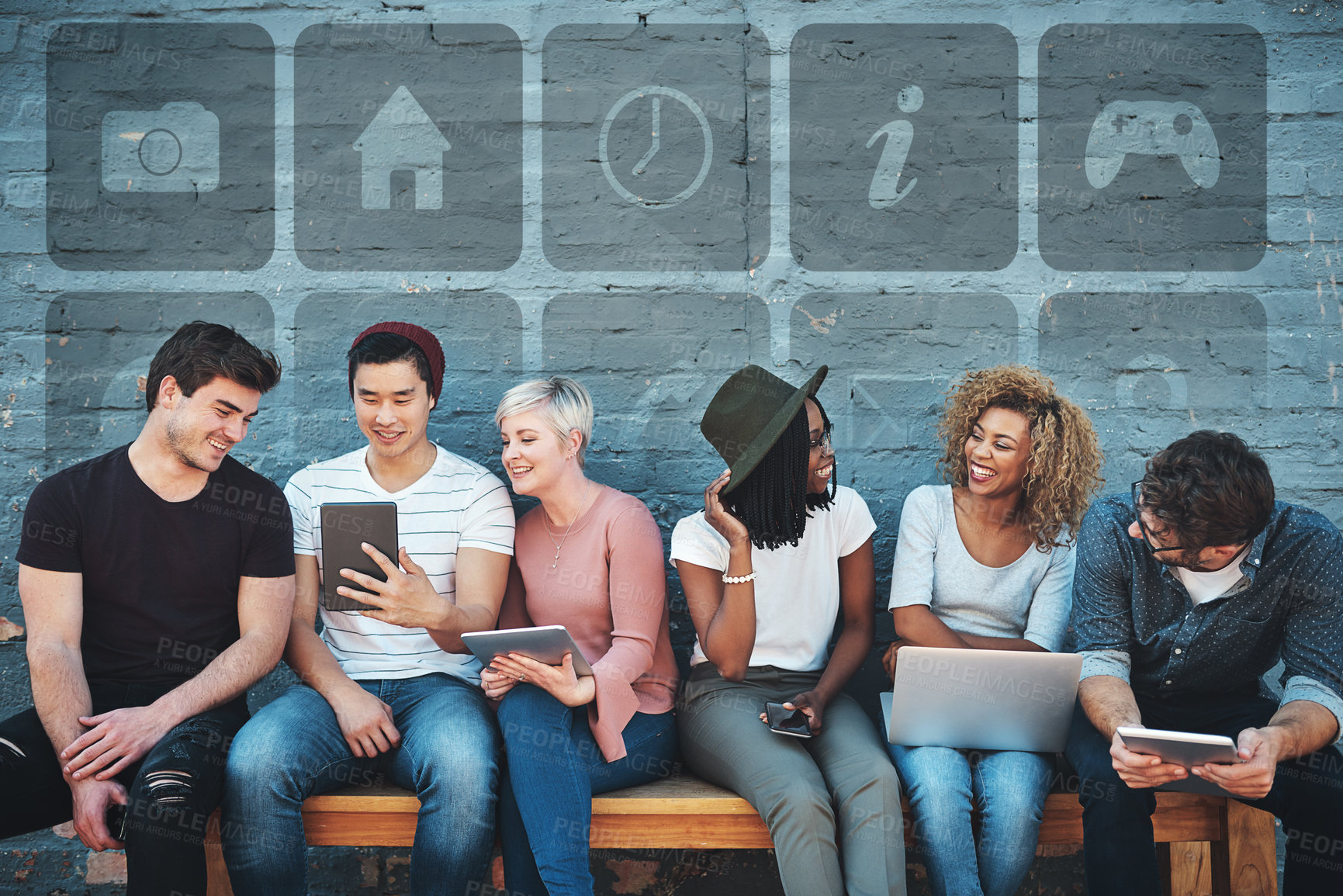 Buy stock photo Technology, diversity and group of young people on a bench browsing social media or the internet. Digital tablets, laptop and multiracial friends networking online together with icons by a gray wall.