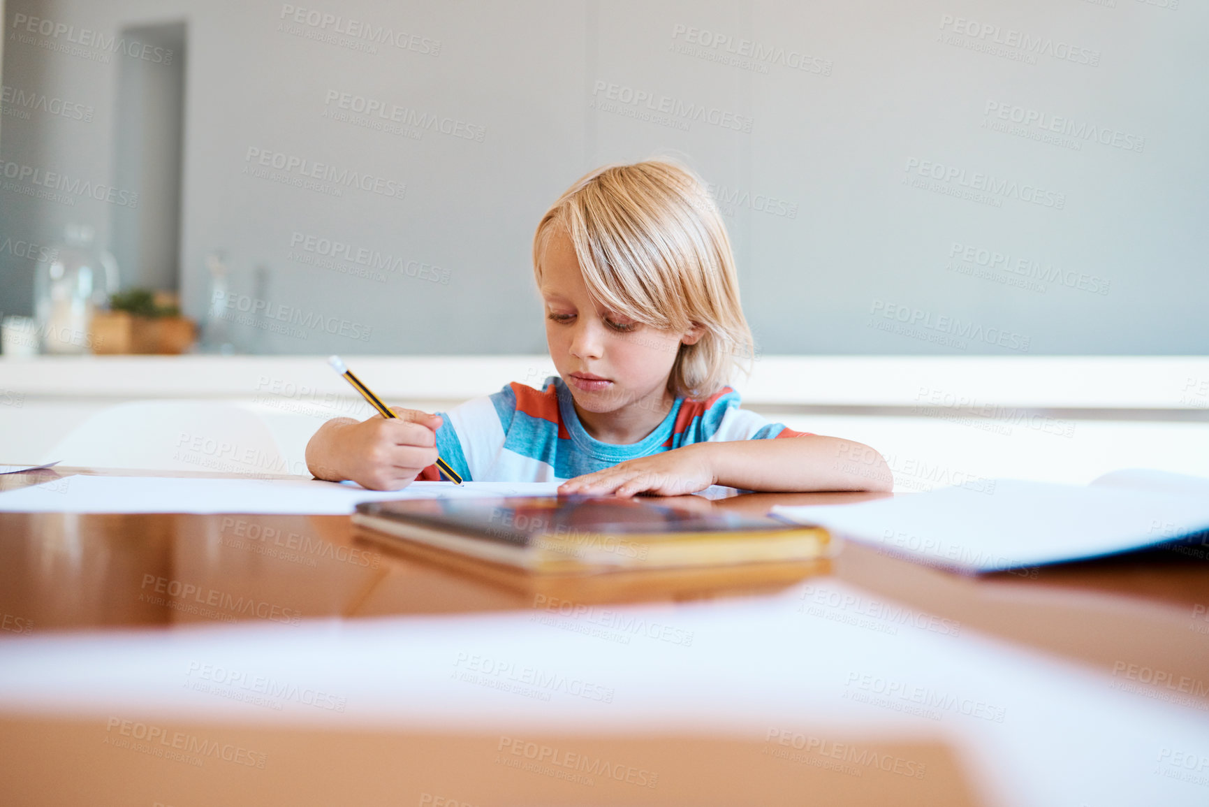Buy stock photo Shot of an adorable little boy doing his homework at home