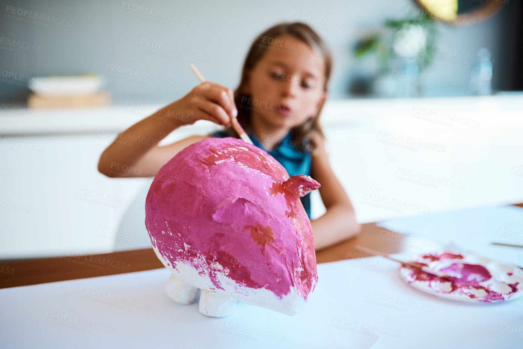 Buy stock photo Girl, child and painting for art in home with pig sculpture, school project or creative assignment at dining table. Education, painter and color fun in house for development, learning and craft hobby