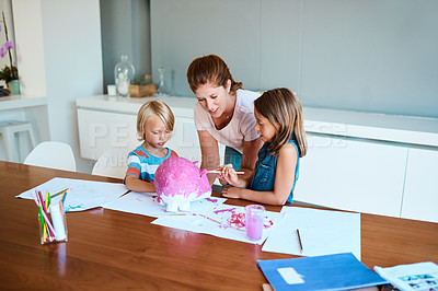Buy stock photo Shot of a young mother helping her two small children with their art project at home