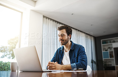 Buy stock photo Shot of a handsome young businessman sitting down and using his laptop to take a video call while working from home