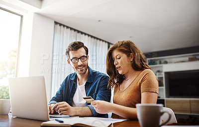 Buy stock photo Shot of a young couple doing some online shopping on a laptop together over the weekend at home