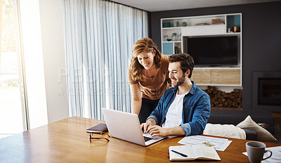 Buy stock photo Shot of a young couple doing some financial planning together on a laptop at home