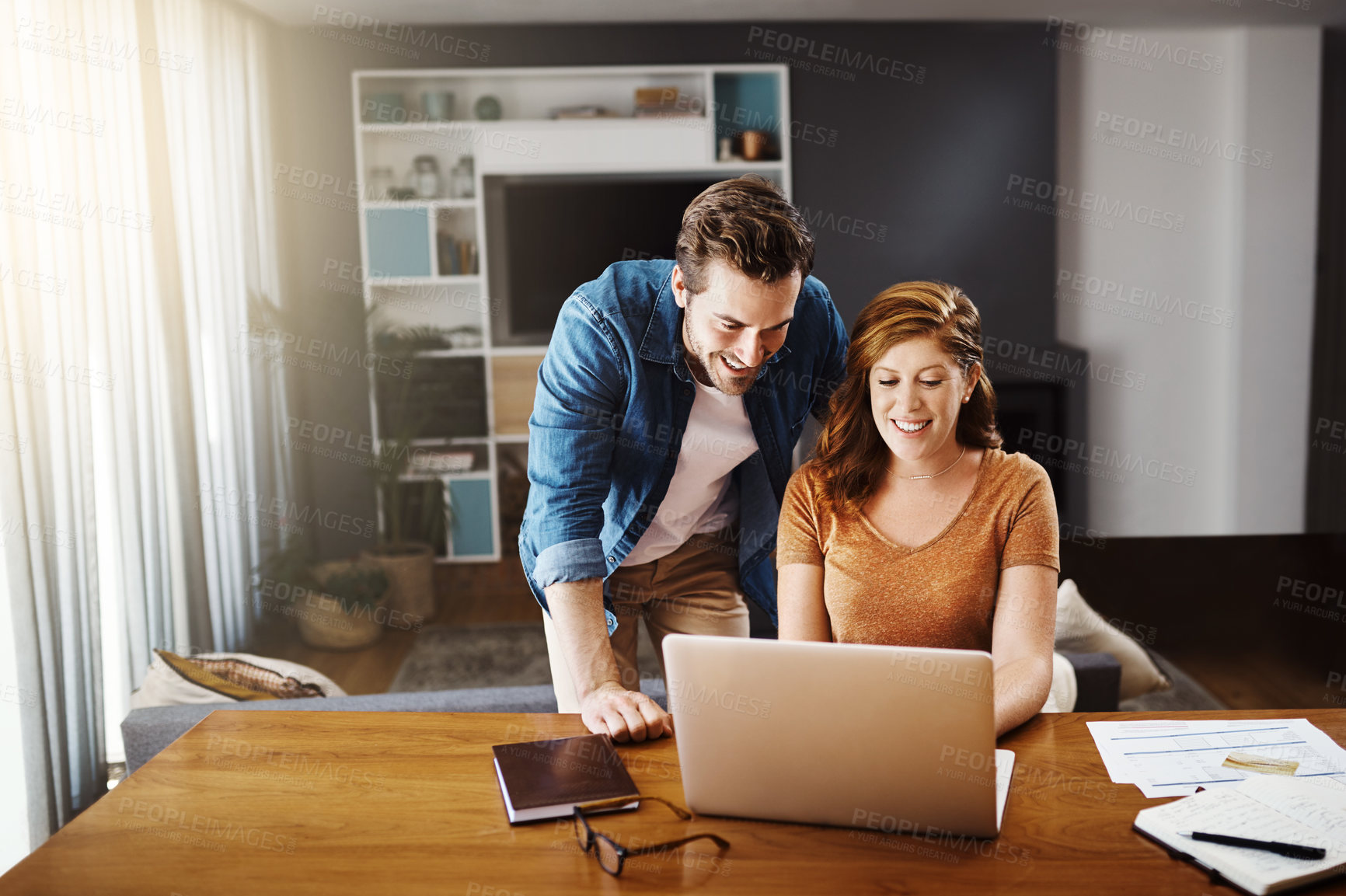 Buy stock photo Shot of a young couple doing some financial planning together on a laptop at home