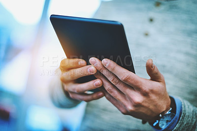 Buy stock photo Shot of an unrecognizable businessman using his digital tablet at work