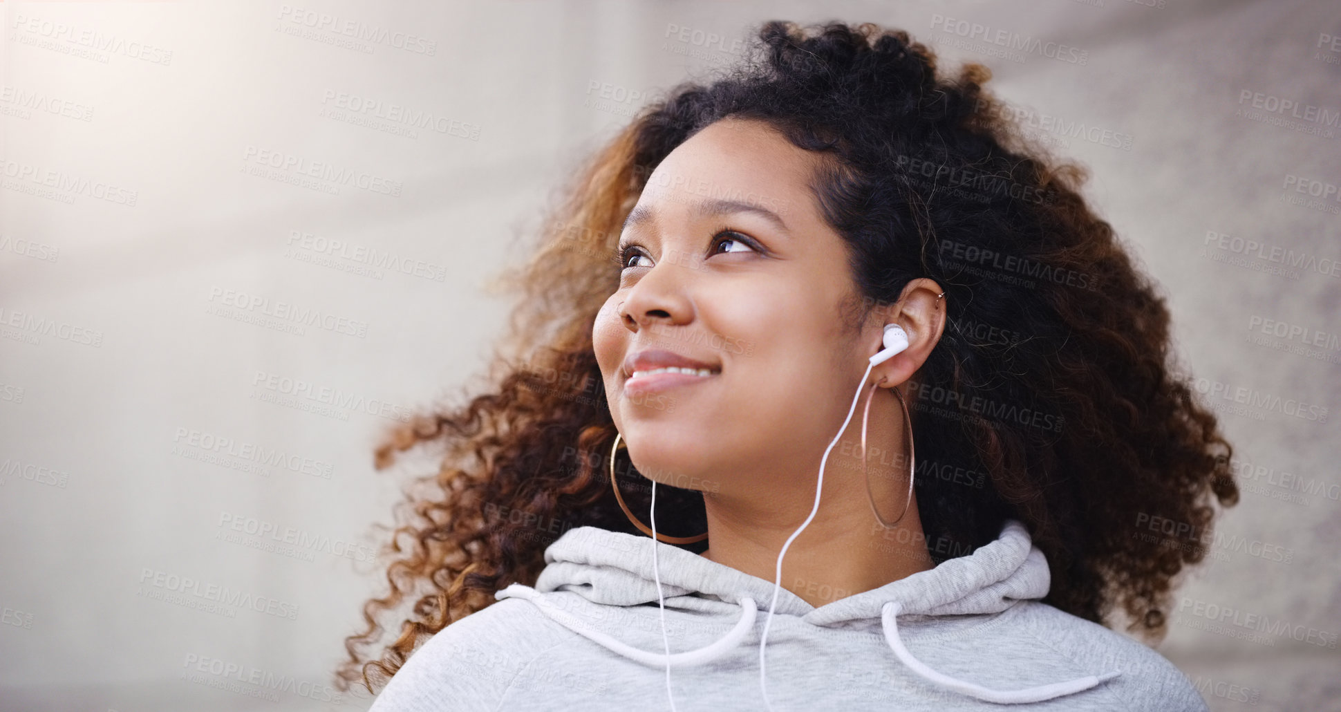 Buy stock photo Happy, thinking and black woman outdoor in city, urban town and street with lens flare by wall in Houston, Texas. Earphones, student and gen z girl with smile for freedom, calm or relax with music