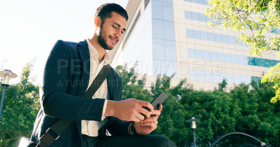 Buy stock photo Shot of a handsome young businessman using his cellphone while commuting to work on his bicycle