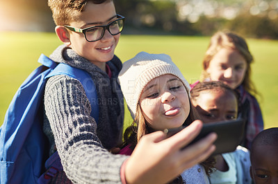 Buy stock photo Shot of a group of elementary school kids taking a selfie together on the school lawn outside