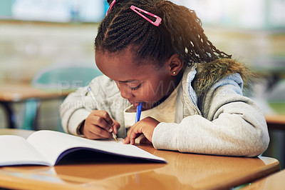 Buy stock photo Shot of an adorable little girl doing her school work in a classroom