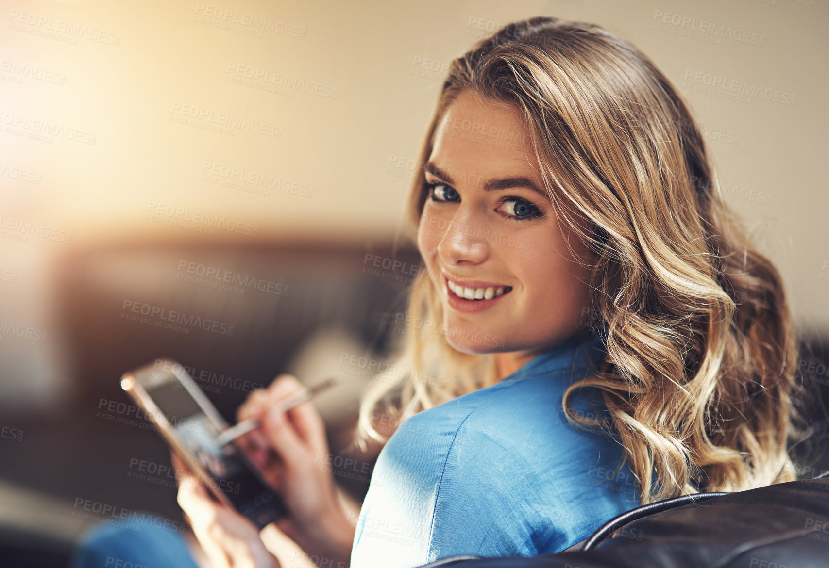 Buy stock photo Shot of a relaxed young woman using a smartphone and stylus on the sofa at home
