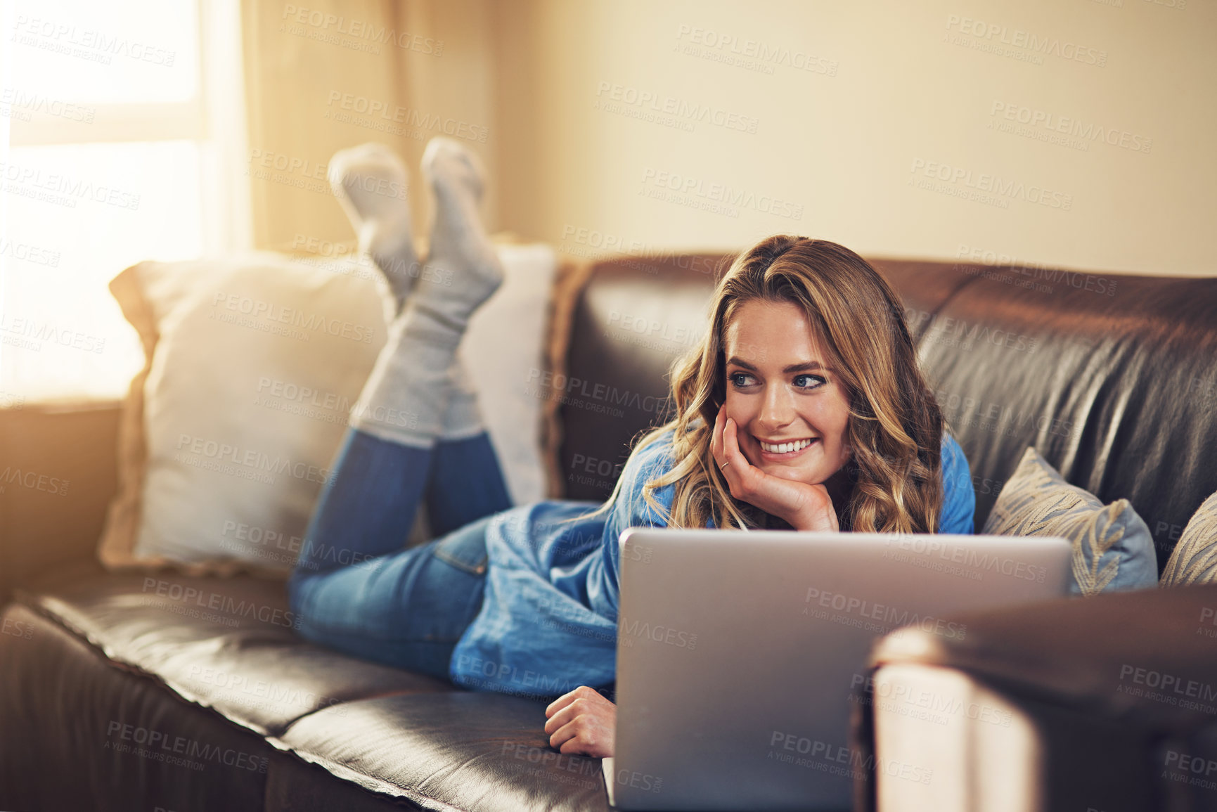 Buy stock photo Shot of a relaxed young woman using a laptop on the sofa at home