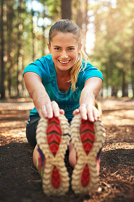 Buy stock photo Shot of a sporty young woman doing stretch exercise while out in nature