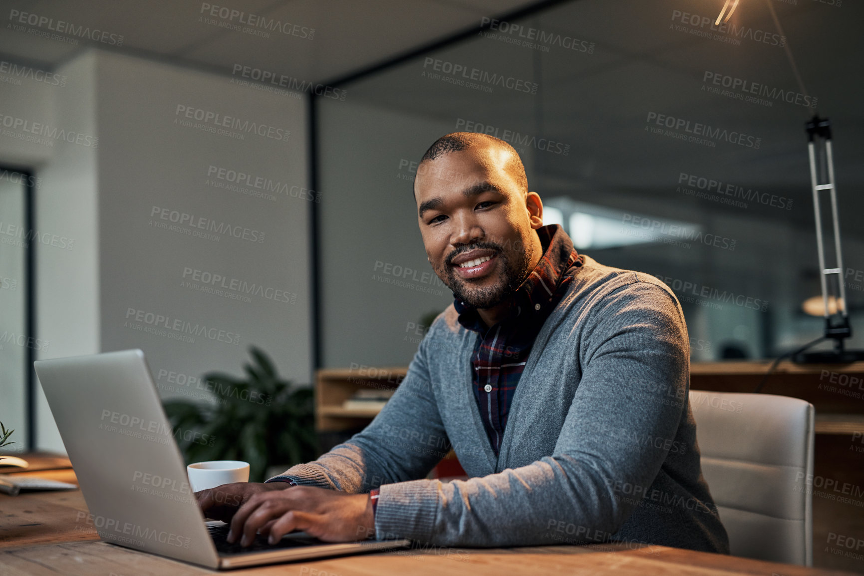 Buy stock photo Portrait of a handsome young businessman working on a laptop in his office