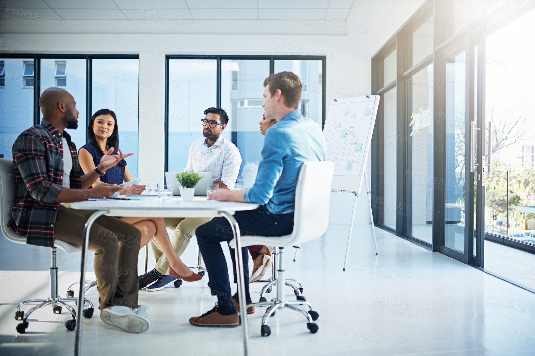 Buy stock photo Shot of a group of young businesspeople discussing ideas with each other during a meeting in a modern office