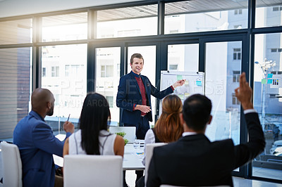Buy stock photo Shot of a young businessman giving a demonstration on a white board to his colleagues in a modern office