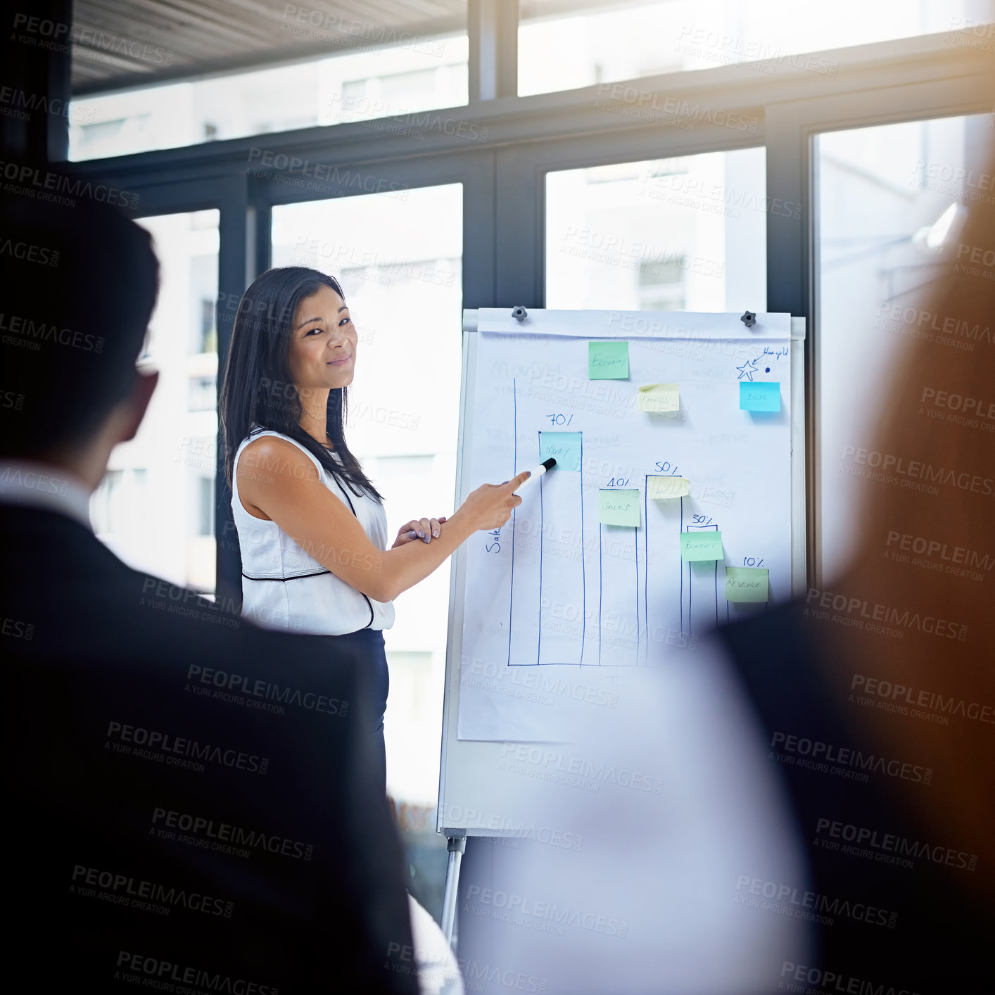 Buy stock photo Shot of a young businesswoman giving a demonstration on a white board to her colleagues in a modern office