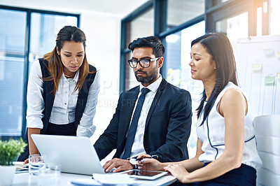 Buy stock photo Cropped shot of a group of young businesspeople using a laptop together in a modern office