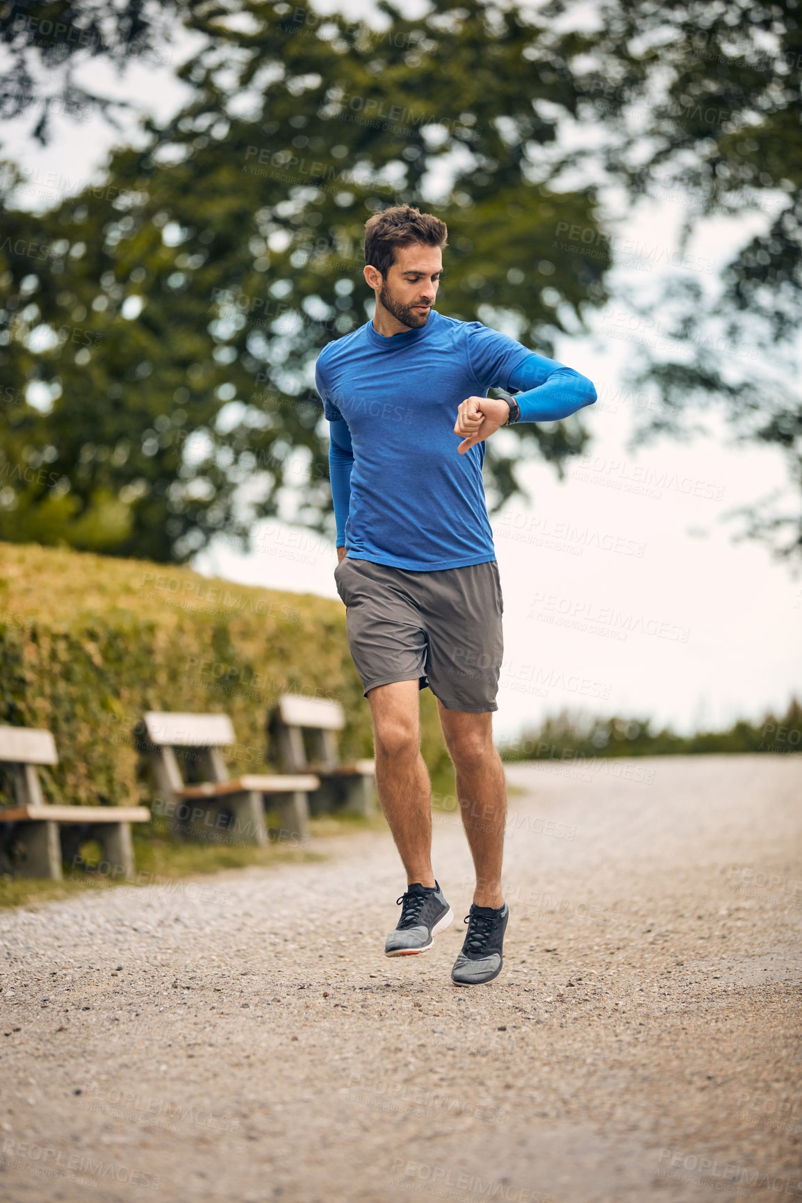 Buy stock photo Shot of a sport middle-aged man looking at the time on his wristwatch while running