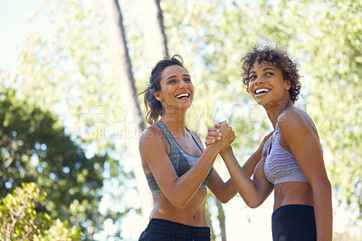 Buy stock photo Cropped shot of two sporty young women exercising outdoors on a sunny day