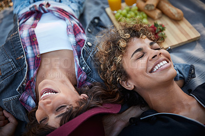 Buy stock photo Cropped shot of two young women lying on a picnic blanket