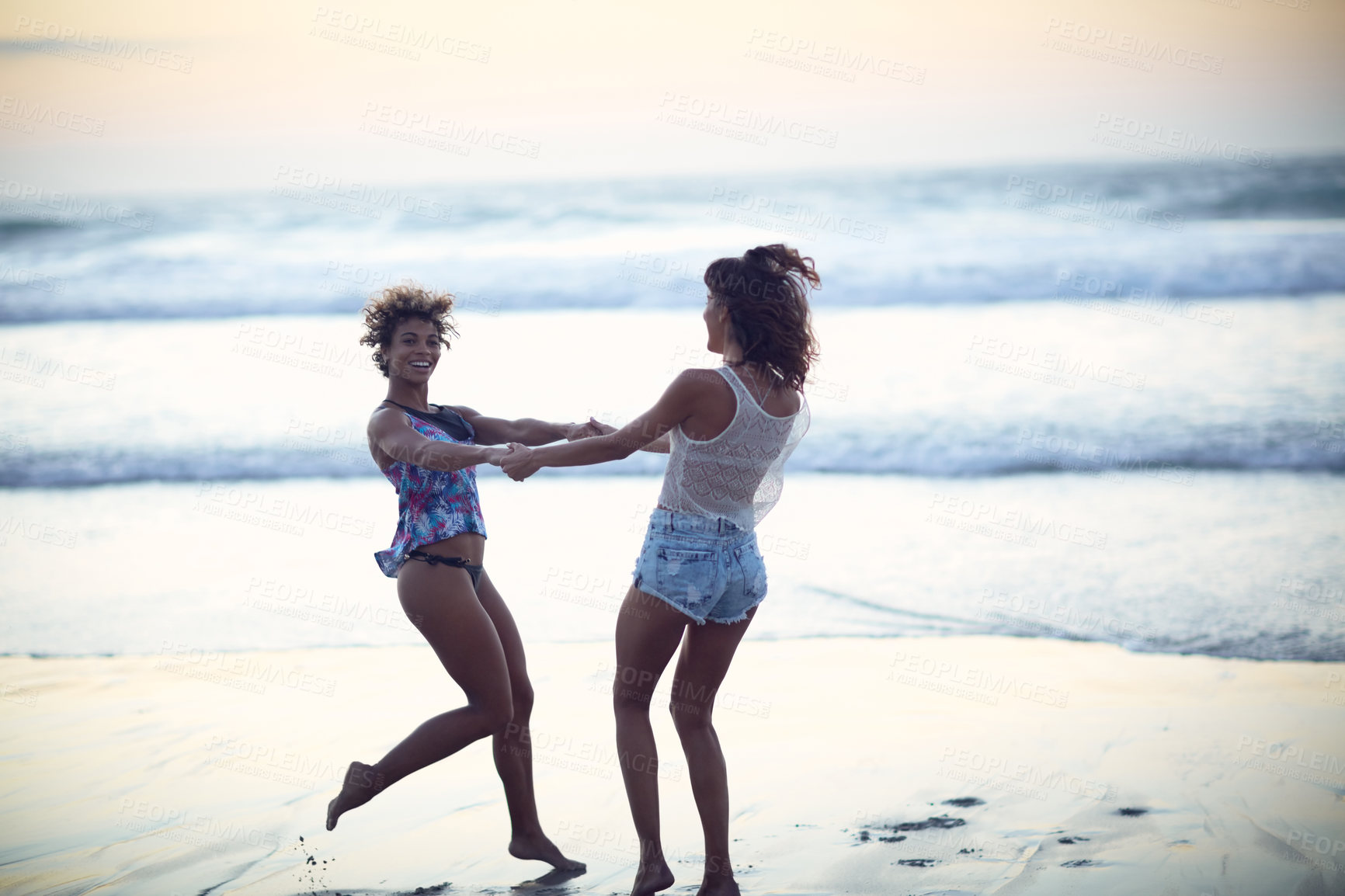 Buy stock photo Shot of two young women enjoying themselves at the beach