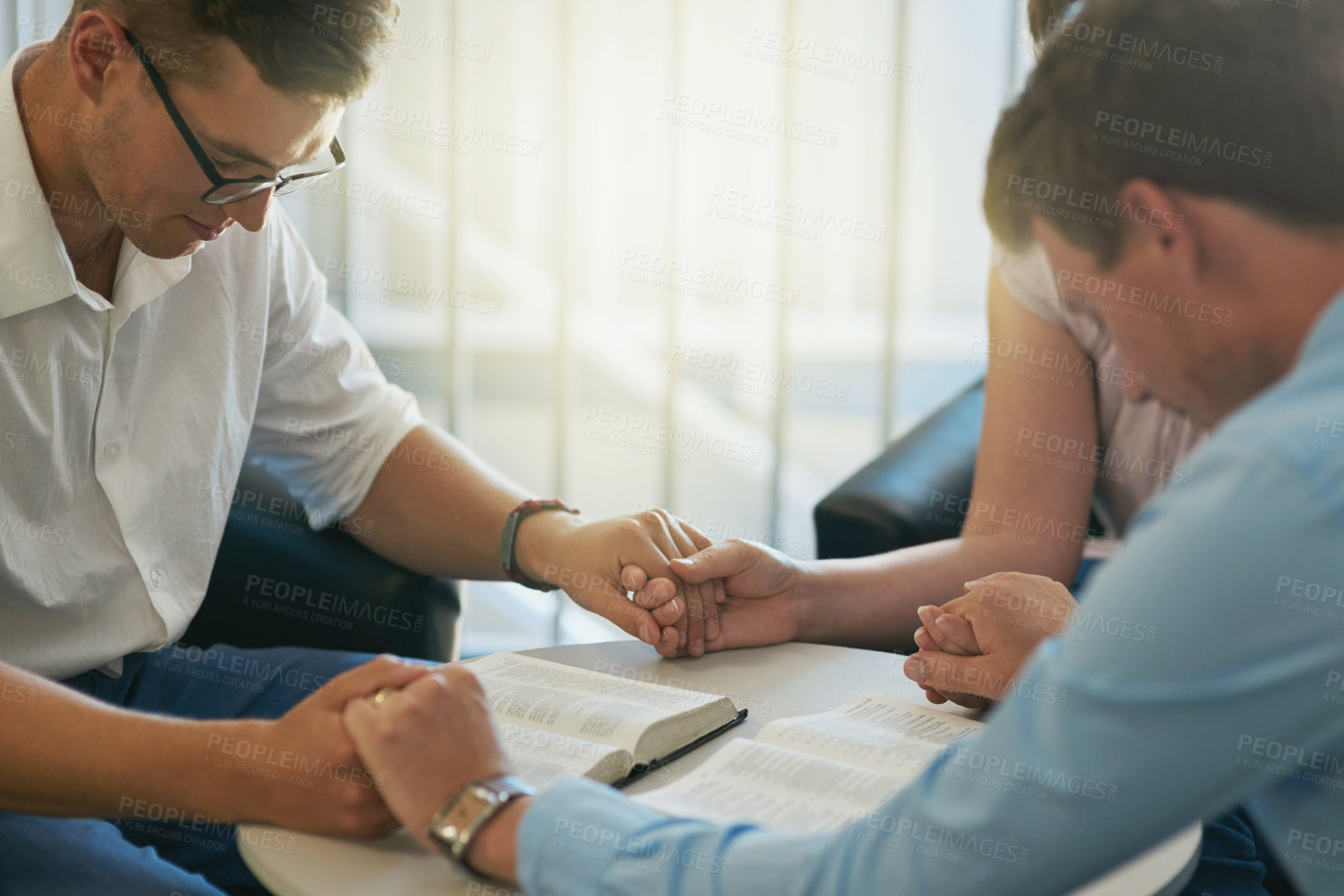 Buy stock photo Shot of a group of young businesspeople holding hands while deep in prayer at work