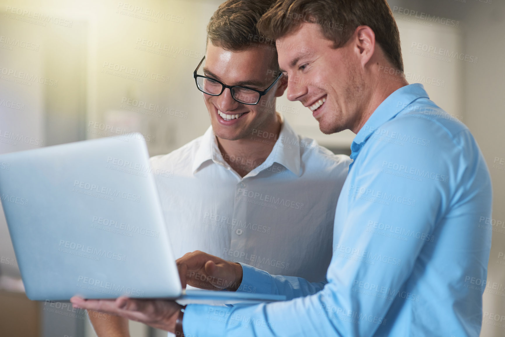 Buy stock photo Shot of two handsome young businessmen working on a laptop together at work