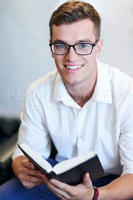 Buy stock photo Portrait of a handsome young businessman reading his bible at work