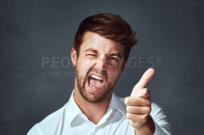 Buy stock photo Studio portrait of a handsome young man making a face against a dark background
