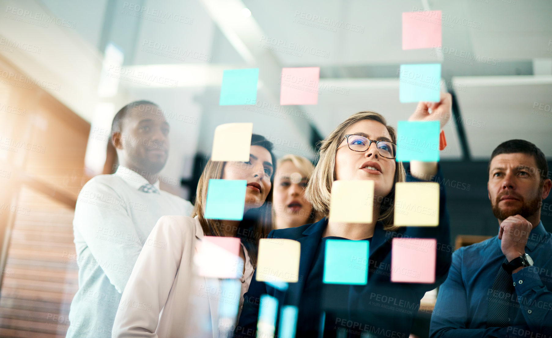 Buy stock photo Creative group or business team planning for innovation with sticky notes on glass wall. Coach or leader sharing vision and mission in a meeting. Manager sharing ideas and explaining strategy
 
