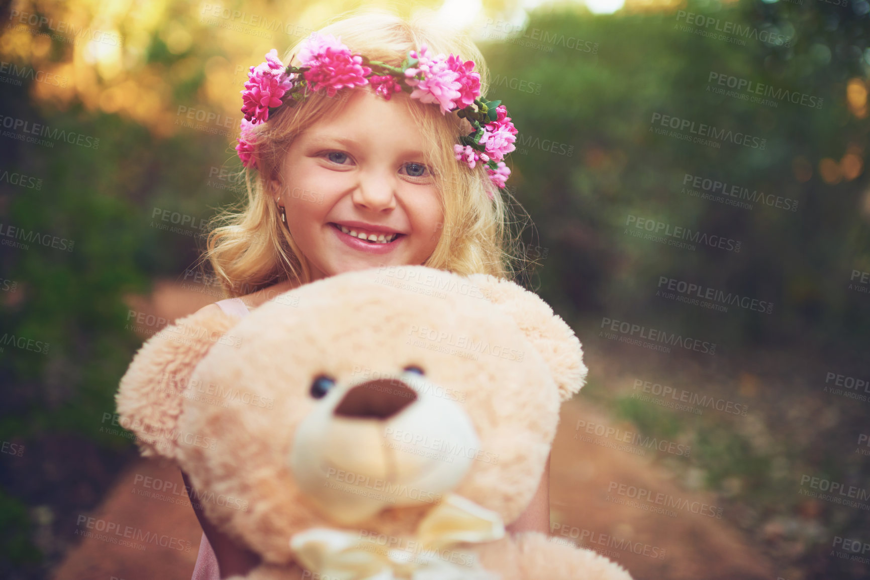 Buy stock photo Shot of a happy little girl holding a teddy bear and looking at the camera while standing in the middle of a dirt road