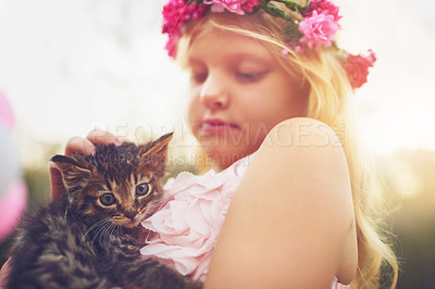 Buy stock photo Shot of a little girl holding a kitten and petting it while standing outside in nature