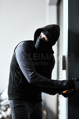 Buy stock photo Shot of a masked criminal busy picking the lock of a door in a garage