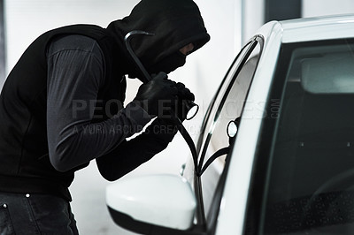 Buy stock photo Shot of a masked man using a steel weapon to break into a car inside a parking lot