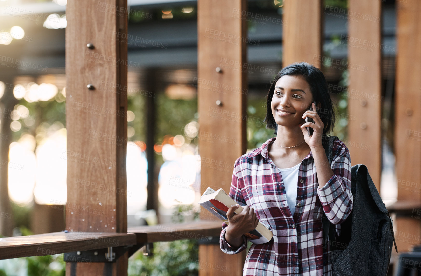 Buy stock photo Girl, university student and phone call with book, outdoor or education with smile for walking at campus. Indian person, happy and smartphone with backpack, contact and chat for learning at college