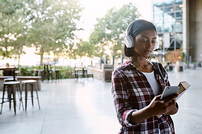 Buy stock photo Cropped shot of an attractive young female student listening to music while walking around campus