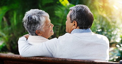 Buy stock photo Rearview shot of an affectionate senior couple sitting down on a bench together and relaxing at the park