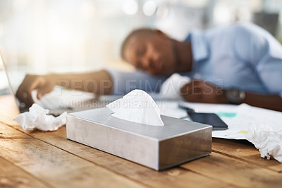 Buy stock photo Shot of a young businessman suffering with a cold while sitting at his desk at work