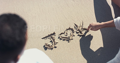 Buy stock photo High angle shot of an unrecognizable couple writing out their initials on sand at the beach