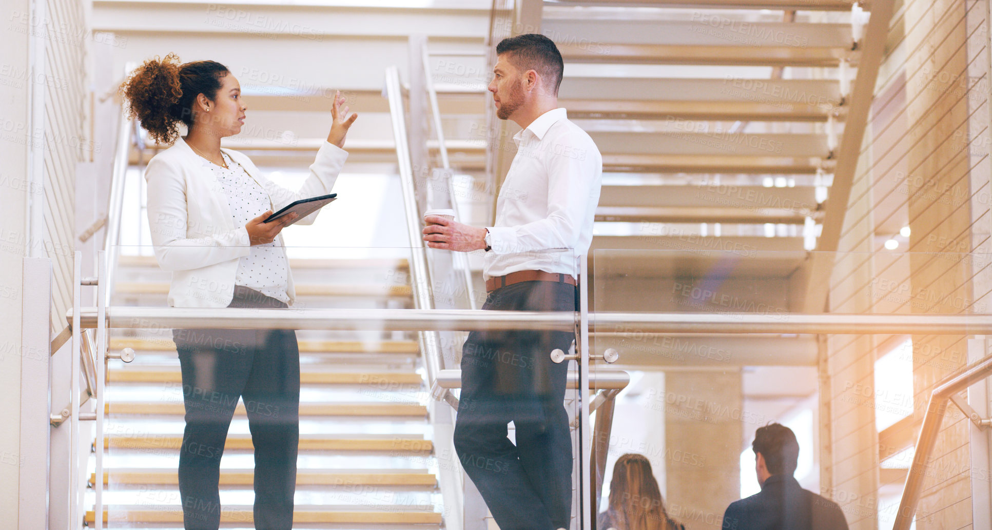 Buy stock photo Cropped shot of two young businesspeople having a discussion while standing in a modern workplace