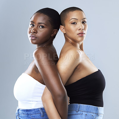 Buy stock photo Portrait of two beautiful women standing back to back against a grey background