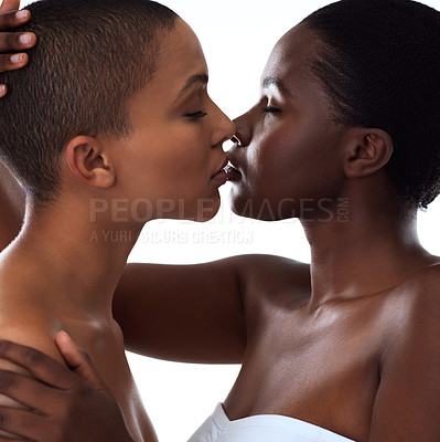 Buy stock photo Studio shot of two beautiful young women holding each other while going in for a kiss and standing against a white background