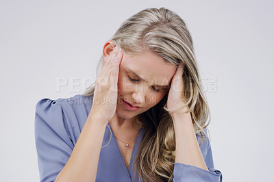 Buy stock photo Shot of a young woman holding her head while suffering from a headache against a grey background