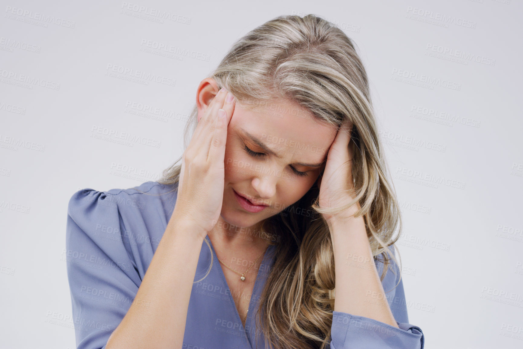 Buy stock photo Shot of a young woman holding her head while suffering from a headache against a grey background