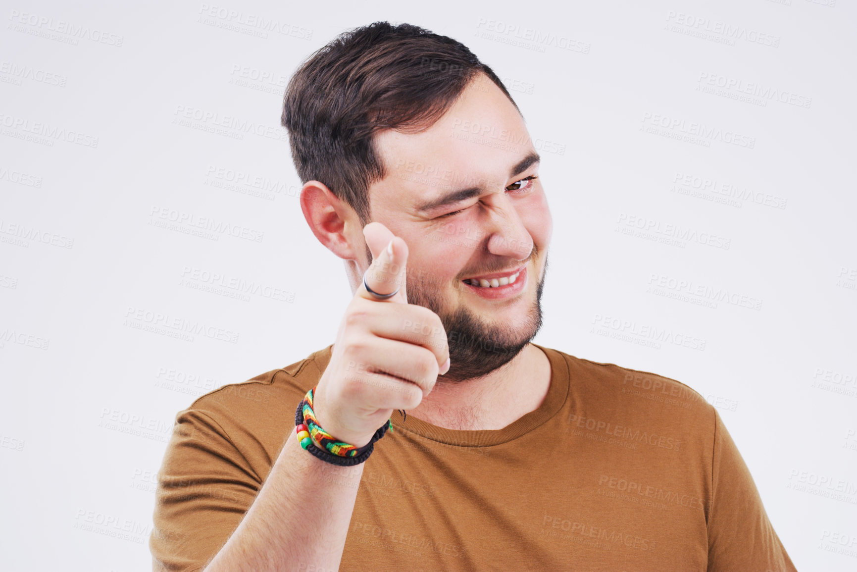 Buy stock photo Portrait of a handsome young man winking and pointing to the camera against a grey background