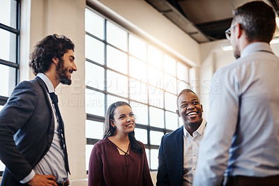 Buy stock photo Cropped shot of a team of laid-back businesspeople chatting during their break in the office